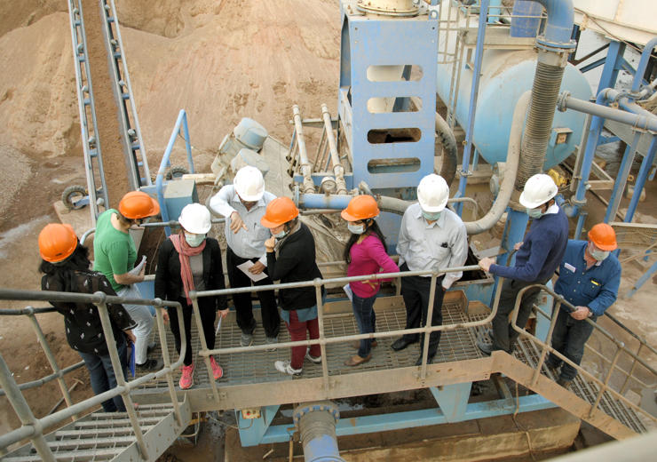 People wearing safety helmets having a discussion on an industrial platform