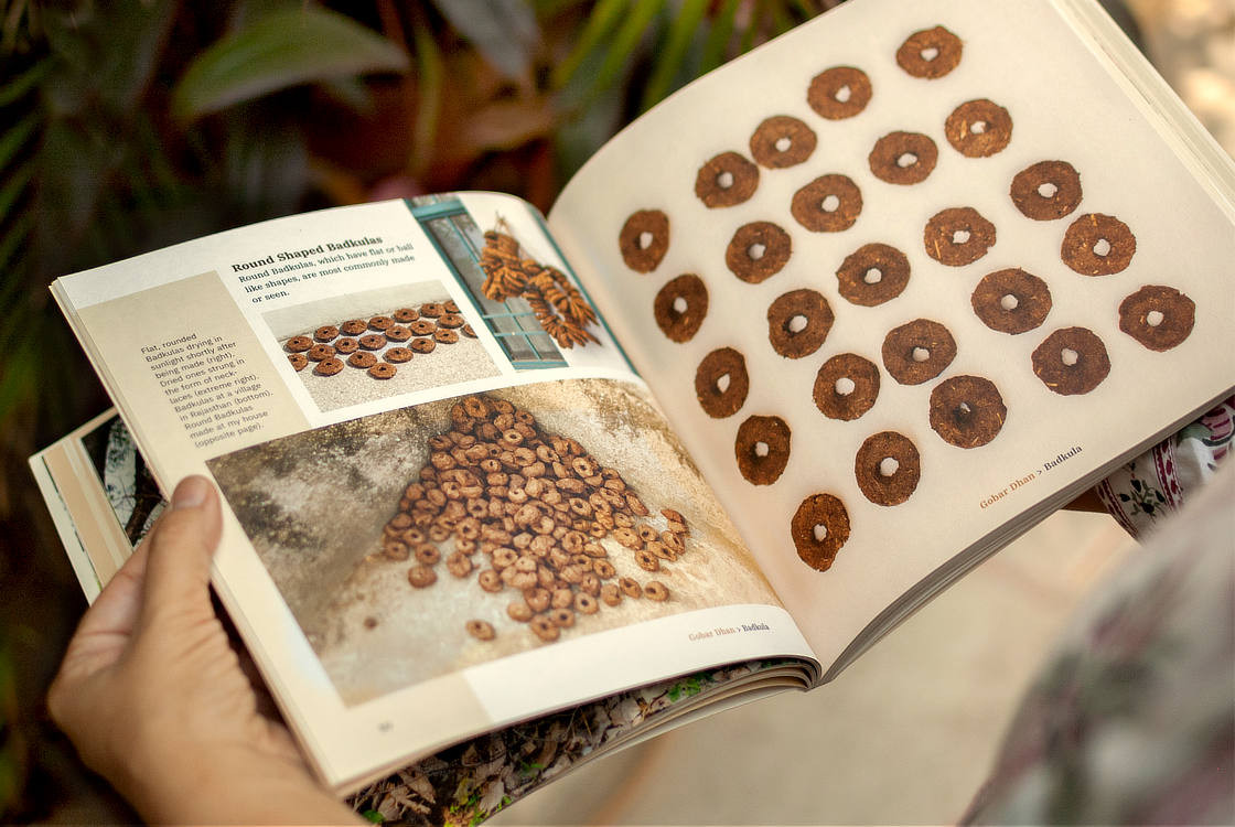 A person holding the book and looking at a spread from the Badkula chapter