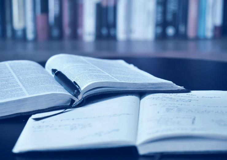 A journal with a pen and a notebook open on a library table