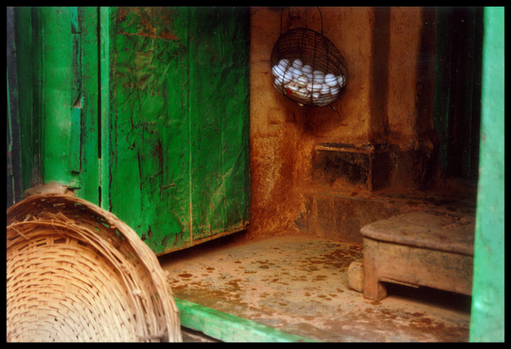 A cane basket and a basket with eggs inside an old store with green and yellow-ochre walls