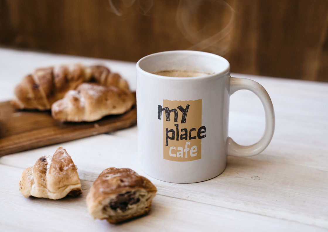 A coffee mug with the logo on it, along with some croissants