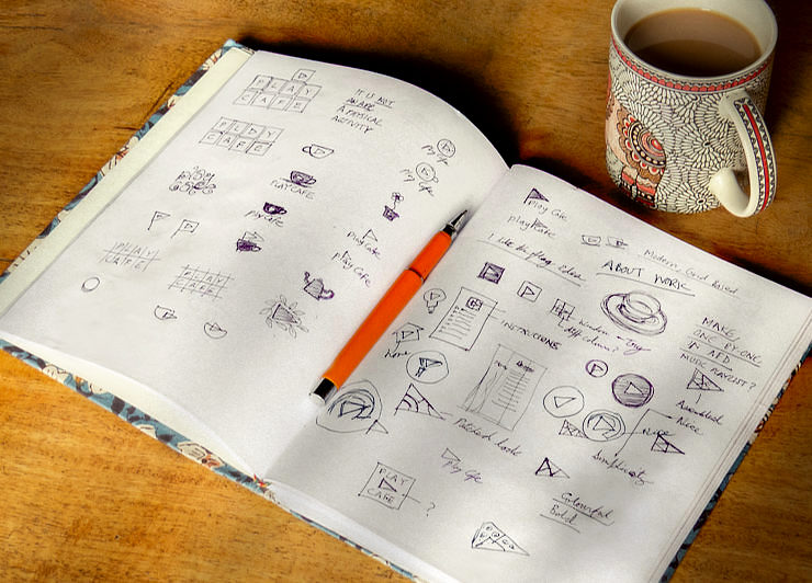 Pages of an open, blank notebook full of logo design sketches