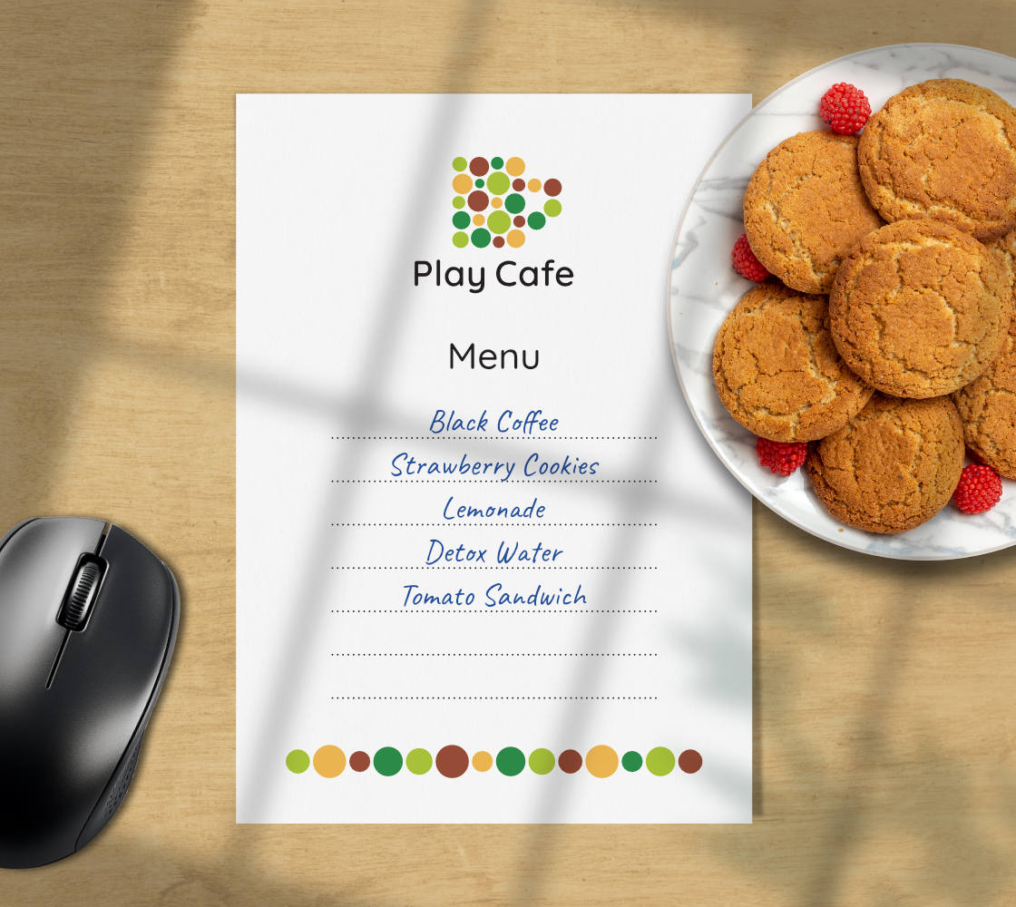 The menu, with food and drink items hand written on it, alongside a computer mouse and a plate of cookies