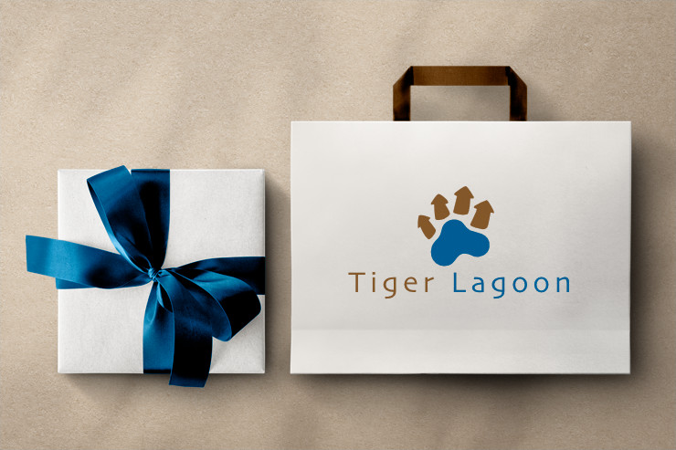 A gift box with a ribbon and a paper bag with Tiger Lagoon logo on it