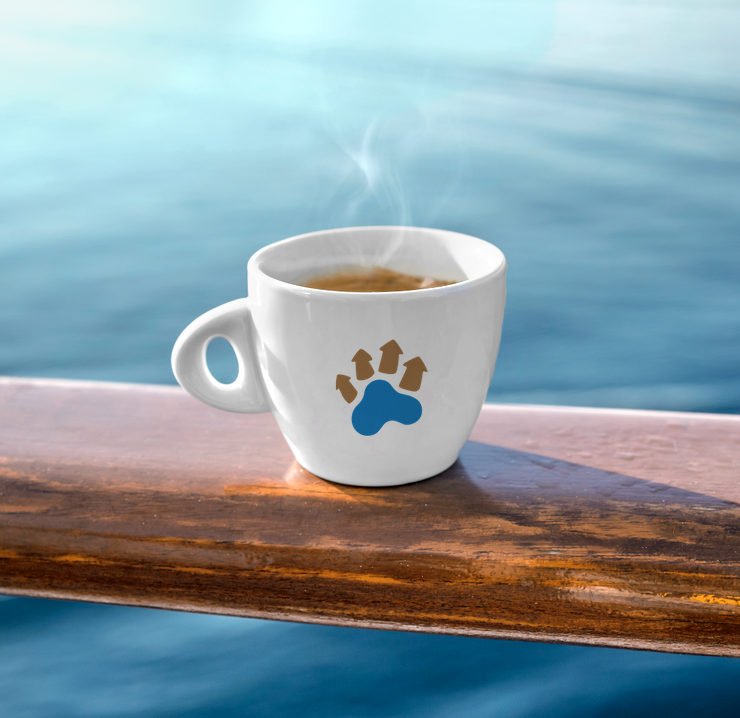 A cup of hot coffee, placed on a railing near the lagoon