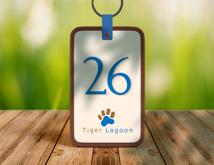 Logo with a large room number on a room keychain, placed outdoor on a wooden table